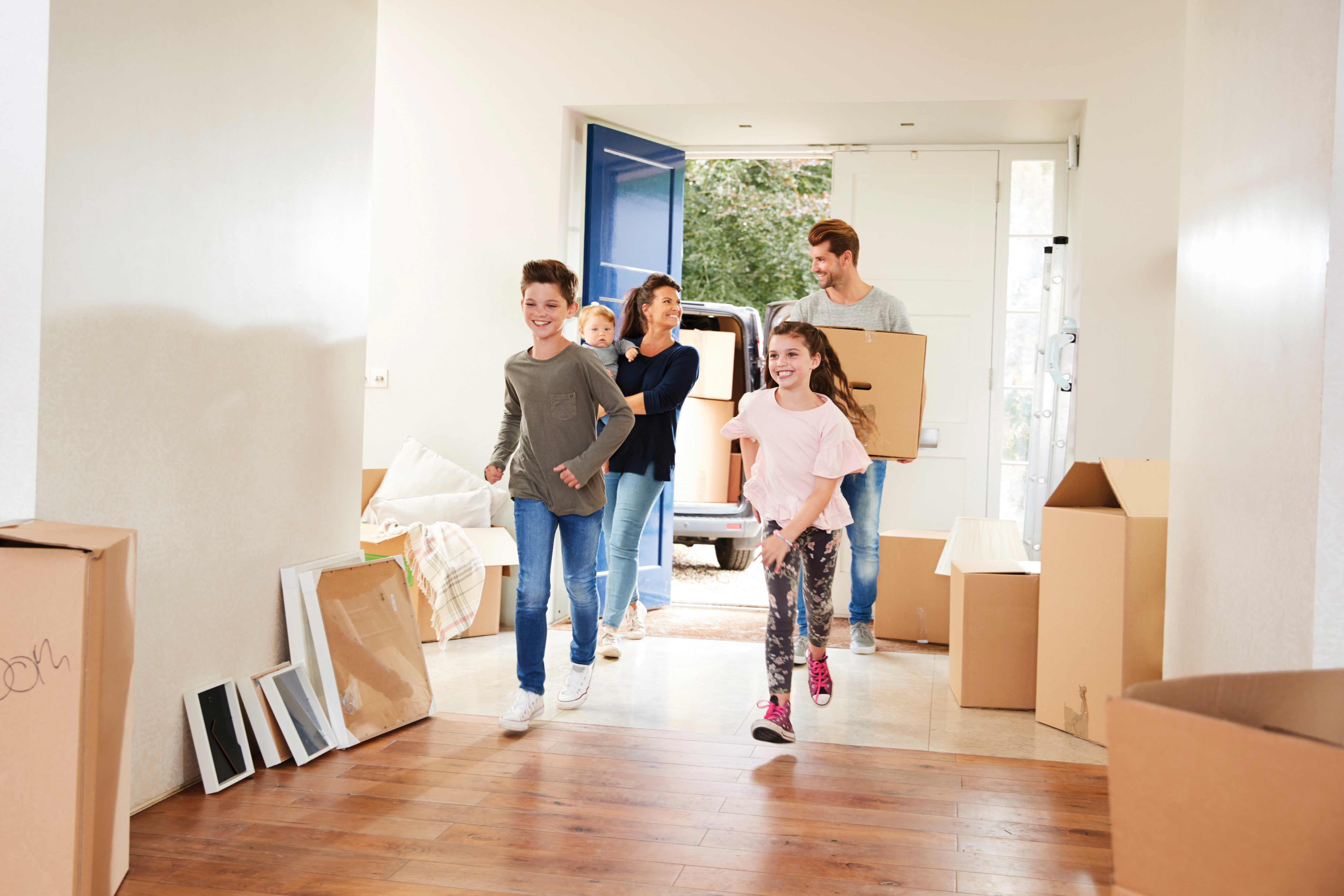 Into new. Family carrying Boxes moving into a Home. Family in a New Apartment. Родители оформляют помещение. Супруги и дети покупаю квартиру.