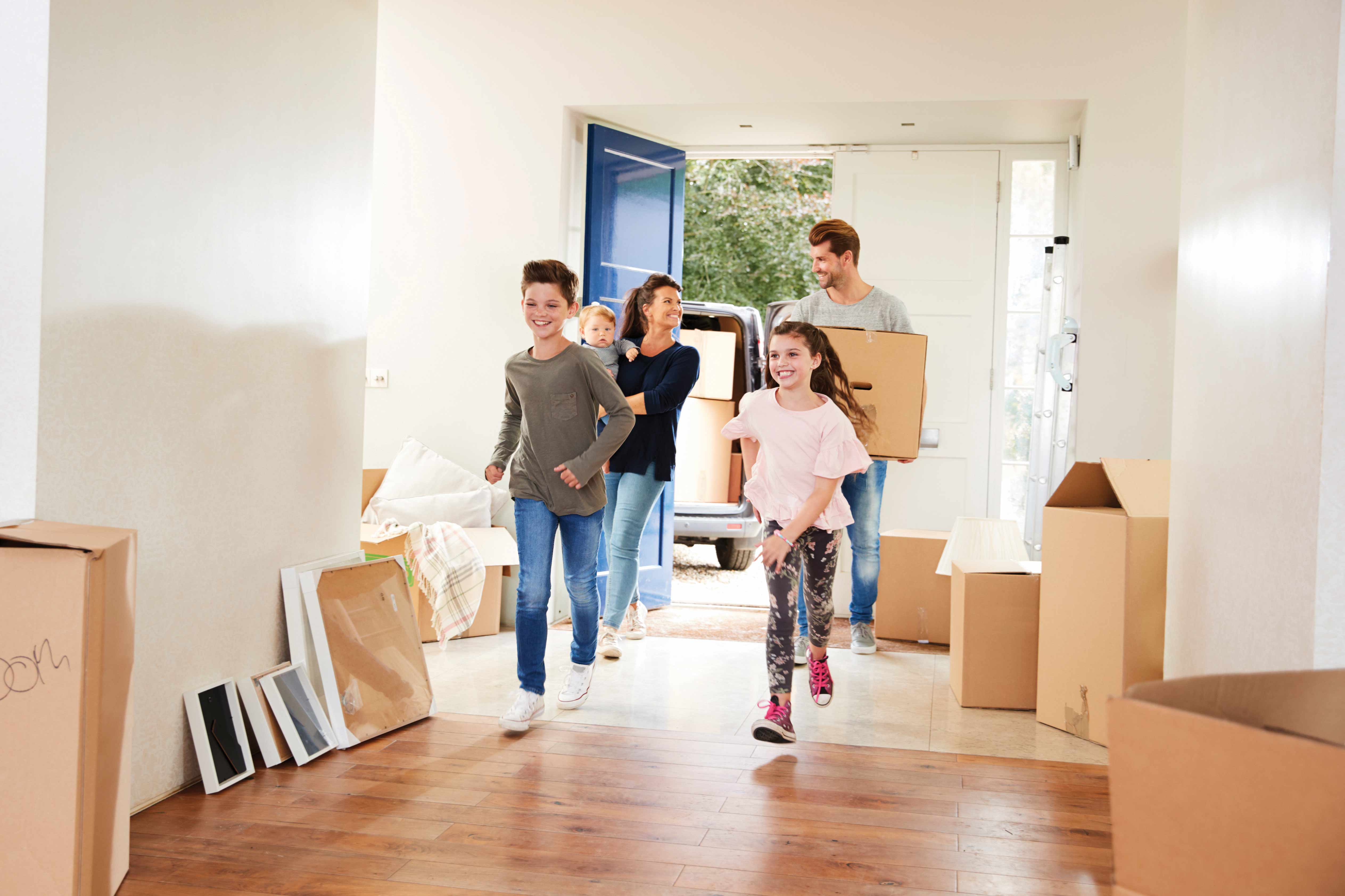 Family Carrying Boxes Into New Home On Moving Day