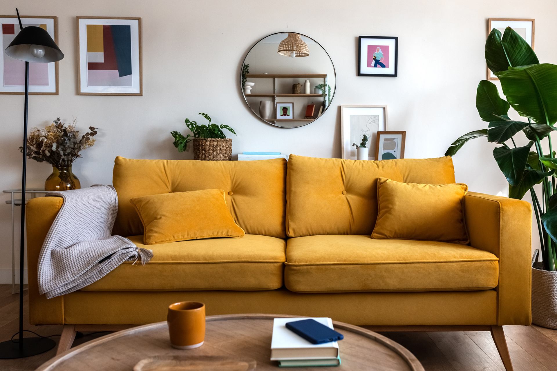 front view of yellow couch in living room with wall art and mirror